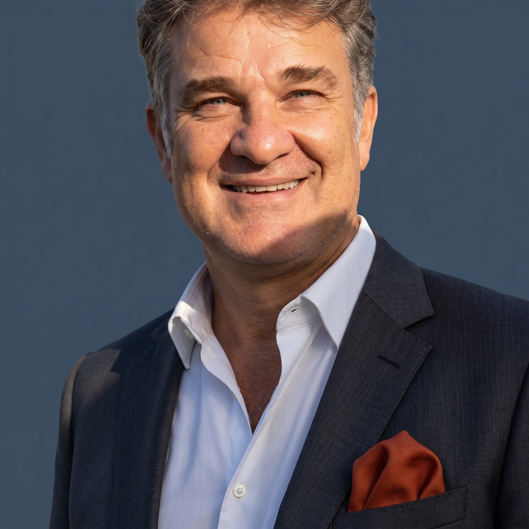 Daniel Santos Cori — Navy suit · slate backdrop